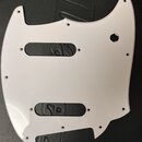 Bílá plastová pickguard pro elektrickou kytaru s dvěma obdélníkovými výřezy na snímače a kulatým otvorem pro ovládací prvek. Povrch je hladký, bez vi…