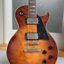 Elektrická kytara s hnědým sluncovým povrchem (sunburst) a dvěma humbuckery. Na těle jsou čtyři černé ovládací knoflíky a černý plechtr zaštít. Povrc…