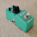 Zelený kytarový efekt pedál značky Ibanez s nápisem TUBE SCREAMER MINI. Na horní straně jsou tři černé ovládací knoflíky s popisky TON, OVERDRIVE a L…