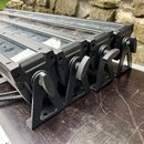 Čtyři černé lineární LED osvětlovací panely s kovovým tělem a průhlednou krytkou. Každý panel je vybaven nastavitelným kovovým stojánkem s plastovým…