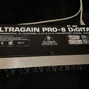 Zadní strana rackového zařízení v černé barvě s hliníkovým předním panelem. Na zadní straně je bílý nápis ULTRAGAIN PRO-8 DIGITAL a PROFESSIONAL 8-CH…