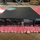 Černý rackový přístroj s kovovým povrchem. Na zadní straně jsou dva kombinované vstupy označené jako left input a right input, konektor aes/spdif, op…