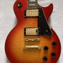 Elektrická kytara s tělem v červeno-žlutém sunburst provedení a viditelnou strukturou dřeva. Nástroj má dva zlaté humbuckery, čtyři černé ovládací kn…