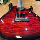 Elektrická kytara s červeným plamenovitým povrchem (flamed maple) a černými okraji. Nástroj má dva humbuckery, chromovaný most a jeden viditelný čern…