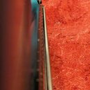 Detailní pohled na hranu modrého trupu elektrické kytary. Je vidět část strun a boční hrana hрифu. Fotografie je rozostřená a neobsahuje žádné čiteln…