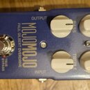Modrý kytarový efekt s nápisy tc electronic, MOJOMOJO a PAUL GILBERT OVERDRIVE. Na horní straně jsou čtyři bílé otočné knoflíky s popisky BASS, TREBL…