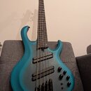 Modrá basová kytara s pětistrunným hmatníkem a dvěma humbuckery. Tělo má matný povrch s tmavším stínováním v oblasti středové části. Na těle jsou umí…