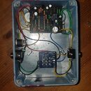 Interiér šedého kovového efektpedálu s dvěma zapínacími spínači. Uvnitř jsou dvě elektronické desky s osazenými součástkami a propojovacími kabely v…