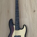 Elektrická basová kytara s tělem v provedení sunburst a krčkem z přírodního dřeva. Na hlavě je viditelné logo Fender. Tělo má krémový pickguard a dva…