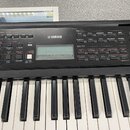 Černý digitální klavír značky YAMAHA. Na ovládacím panelu jsou viditelné nápisy jako SOUND CONTROL, VOICE a SONG / STYLE. V pravém dolním rohu panelu…