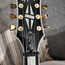 Hlava elektrické kytary v černé barvě s bílým lemováním. V horní části je bílé logo Epiphone a níže nápis Les Paul MKH ORIGINS CUSTOM. Nástroj má zla…