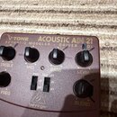 Hnědý kytarový pedál s nápisy V-TONE ACOUSTIC ADI 21 a ACOUSTIC MODELER — DRIVER — DI. Na horní straně jsou čtyři otočné knoflíky s popisky TREBLE, M…