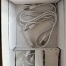 Bílá krabička s několika bílými kabely a sluchátky. Na jednom z kabelů je viditelný nápis 30AWG VW-1 80°C 30V CABLE. V horní části jsou dva konektory…