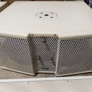 Bílý kovový reproduktorový box s perforovaným povrchem. Horní strana je plochá s kulatým otvorem uprostřed a dvěma menšími otvory v rozích. Na horní…
