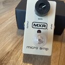 Bílý kytarový pedál s nápisem MXR a označením micro amp. Na horní straně se nachází černý otočný knoflík s popiskem GAIN, červená kontrolka a průhled…
