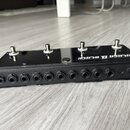 Černý obdélníkový přístroj s kovovou horní deskou, na které jsou čtyři stříbrné přepínače. Na pravé straně je bílý nápis ULASA B BLACK. Přední strana…