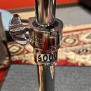 Detail chromovaného kovového stojanu s utahovacím motýlkovým šroubem. Na šroubu je vyryto "SONOR" a na spodní části spojovacího mechanismu je nápis "…