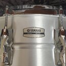 Kovový buben stříbrné barvy s chromovaným obručím a ladicími šrouby. Na korpusu je nalepený štítek s nápisy HANDCRAFTED SINCE 1967, YAMAHA, MODEL, SE…
