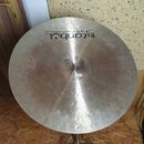 Kruhový činely z kovového materiálu s viditelným broušením povrchu. Na horní části je černý nápis „istanbul“ a nad ním v kurzivě text „Agop Handmade…