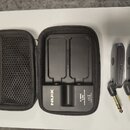 Černý bezdrátový systém NUX C-5RC v přepravním pouzdře s dvěma vysílači. Na nabíjecím docku je nápis NUX, C-5RC WIRELESS SYSTEM a RECHARGE. Vysílače…