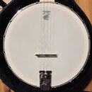 Bílá membrána banjona s kovovým obručím a úchytnými šrouby. V horní části je černý nápis DEERING a pod ním menší text Banjo Company s doprovodnou gra…