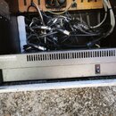 Kryt v rackovém pouzdře s instalovaným zdrojem napájení. Na zařízení je nápis MACKIE 220-WATT POWER SUPPLY a červený vypínač s nápisem POWER. V horní…