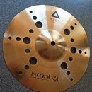 Zlatavý kovový činel s otvory různých velikostí v celém těle. Na povrchu je nápis XIST 10" ION Splash s trojúhelníkovým logem a v dolní části nápis i…
