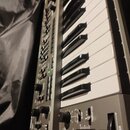 Šedý klavír nebo synthesizér s bílými a černými klávesami. Na ovládacím panelu jsou viditelné nápisy TRANSPOSE, BENDER a LFO. Jsou zde rovněž různé o…