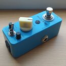 Modře lakovaný kytarový efekt s bílými nápisy Blue Comp, SUSTAIN, LEVEL a OUTPUT. Na horní straně se nachází jeden velký krémový knoflík, dva malé če…