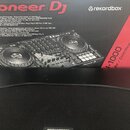 Fotografie zachycuje červenobílou krabici s nápisem Pioneer DJ a logem rekordbox. Na obalu je zobrazen černý DJ 컨트롤러 s nápisem DDJ-1000. V popisu na…