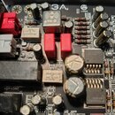 Detailní záběr na elektronickou základovou desku s různými komponenty, jako jsou kondenzátory, rezistory a integrované obvody. Na desce je viditelné…