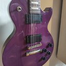 Fialová elektrická kytara s dvěma humbuckery a čtyřmi černými ovládacími knoflíky. Nástroj má chromovaný kobylník a strunovník. Na těle nejsou vidite…