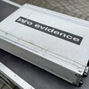 Stříbrný transportní kufr z hliníku s texturovaným povrchem. Uprostřed je černý nápis pro evidence. Povrch vykazuje známky opotřebení v podobě škrába…