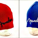Dvě pletené čapky typu beanie, jedna v červené a druhá v modré barvě. Obě mají na přední straně vyšívaný nápis Fender v charakteristickém stylu značk…