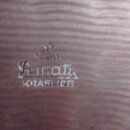 Detail dřevěného povrchu s vyrytým nápisem. Je zde vidět logo „Linnati“ a pod ním slovo „KRASLICE“. Nad logem je umístěn malý, méně čitelný symbol.