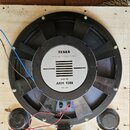 Na dřevěné desce je umístěn velký černý reproduktor s magnetem. Na středovém bílém štítku je nápis TESLA, MADE IN CZECHOSLOVAKIA, 50 W-8Ω a ARM 9308,…