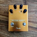 Zlatý kytarový efekt s nápisem MTG TUBE TREMOLO a logem Fender. Na horní straně jsou tři černé otočné knoflíky s popisky LEVEL, SPEED a INTENSITY, př…