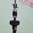 Detailní záběr na spojovací mechanismus kovového stojanu. Je vidět stříbrný šroub s motýlkovým knoflíkem a černá pěnová izolace na středové části. Sp…