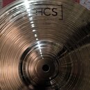 Kruhový kovový činel s koncentrickými rýhami na povrchu. V horní části je černý nápis HCS v rámečku, pod ním text MADE IN GERMANY a dále 12" Splash.…