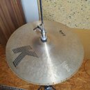 Kruhové činely z mosazného kovu s viditelným broušením povrchu. Na ploše je černý grafický symbol šipky a nápisy „Hi Hat TOP“ oraz „14" 105Hz L21“. V…