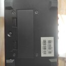 Spodní strana černého elektronického zařízení s gumovými nožičkami. Na bílé nálepce je uveden nápis UPC, RC-500 a čísla T761294516751 oraz (21) D6N10…