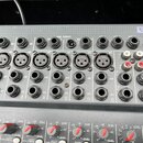 Detailní záběr na horní panel šedého mixážního pultu se značkou SPI a nápisem By Sou. Jsou vidět řady vstupních konektorů označených jako DIR, MIC (X…