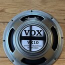 Kruhové reproduktory s kovovým rámem v stříbrné barvě. Uprostřed je štít s nápisy VOX, VX10 a CUSTOM CELESTION 10" SPEAKER. Povrch rámu vykazuje drob…