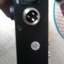 Detailní pohled na černý panel elektronického zařízení. Je zde vidět vypínač s nápisem POWER, jeden XLR konektor a malý kulatý bílý štítek s nečiteln…