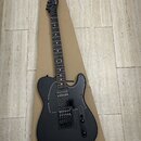 Černá elektrická kytara s matným povrchem těla a lesklým pickguardem. Na hlavě hředu je viditelný nápis Andy Fletcher. Nástroj má dva humbuckery a dv…