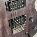 Detail elektrické kytary s tmavým dřevěným povrchem. Nástroj má dva černé humbuckery a chromovaný kobylník. Na kytáře jsou vidět dvě černé ovládací k…
