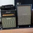 Sada kytarových zesilovačů značky Marshall. Vlevo je naskládaná hlava zesilovače s ovládacím panelem a pod ní kombo zesilovač se zlatým mřížkováním,…
