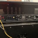 Zadní strana kytarového zesilovače značky Marshall s černým kovovým šasi a horní ventilační mřížkou. Na zadním panelu jsou viditelné konektory, ovlád…
