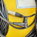 Černý audio kabel s kovovými konektory. Na povrchu kabelu je opakovaně bílý nápis HIGH PERFORMANCE a MICROPHONE CA. Na jednom z konektorů je vidět ma…