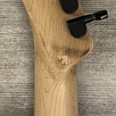 Záběr na hmatník a hlavu kytary z přírodního dřeva s šesti černými ladičkami. Na hlavě je čitelný nápis Fender, Designed and Backed by Crafted in Ind…